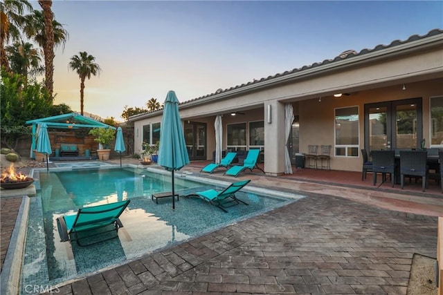 pool at dusk with a patio area and ceiling fan