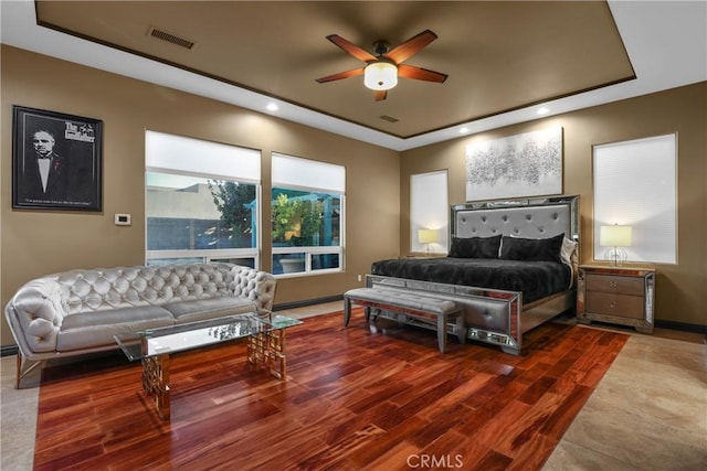 bedroom featuring ceiling fan, a raised ceiling, and wood-type flooring