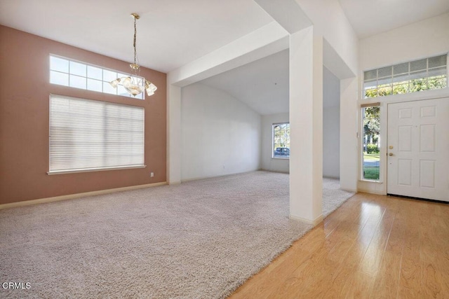 carpeted foyer entrance with an inviting chandelier and vaulted ceiling