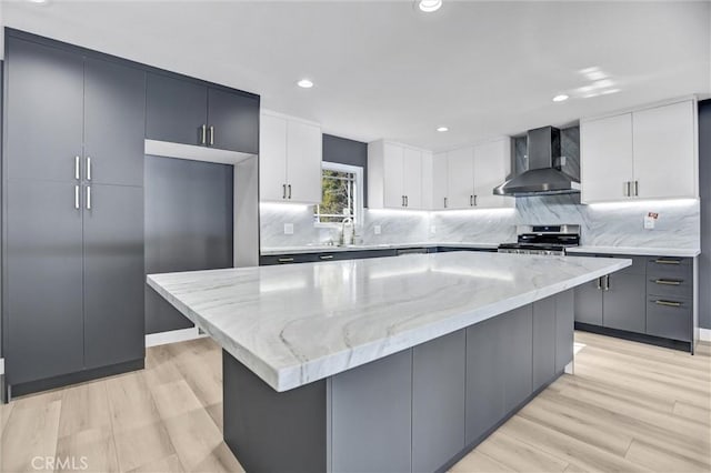 kitchen featuring light stone counters, stainless steel range, wall chimney exhaust hood, and a kitchen island