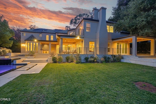 back house at dusk with a yard and a patio area