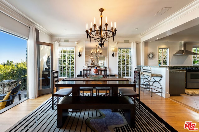 dining space with ornamental molding, a notable chandelier, and light hardwood / wood-style flooring