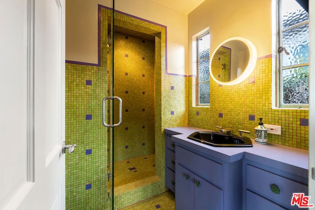 bathroom featuring a tile shower, vanity, and tile walls