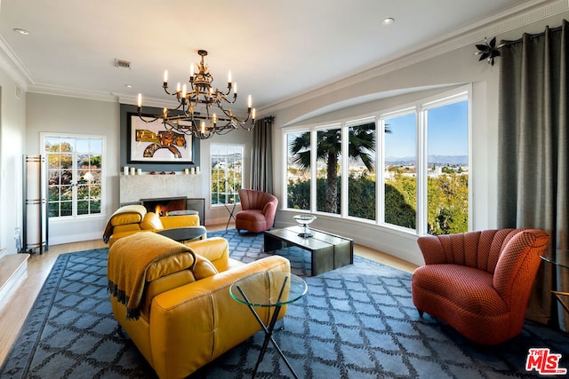 interior space featuring a tile fireplace, an inviting chandelier, crown molding, and hardwood / wood-style flooring