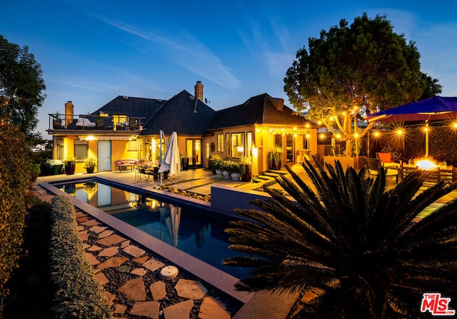 pool at dusk featuring a patio