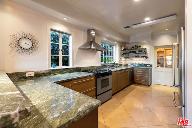 kitchen featuring sink, light tile patterned floors, dark stone counters, ventilation hood, and appliances with stainless steel finishes