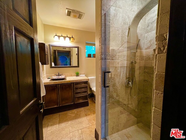 bathroom featuring toilet, tiled shower, and vanity