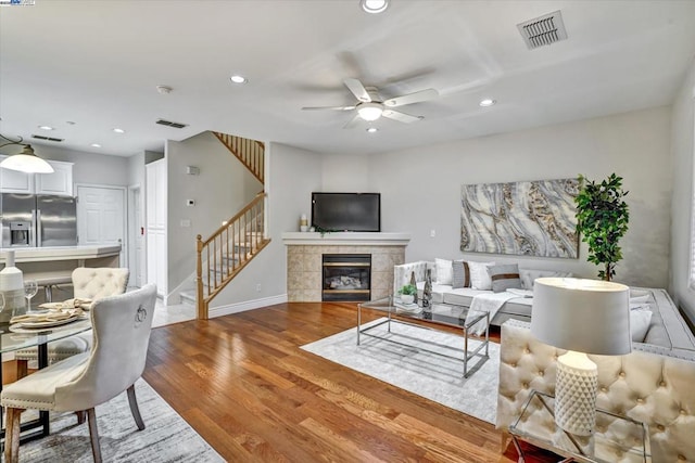 living room featuring wood-type flooring, ceiling fan, and a fireplace