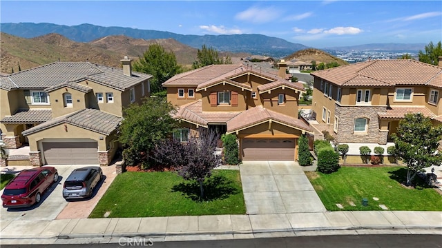 view of front of property with a garage, a front yard, and a mountain view