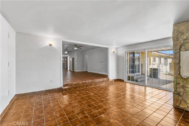 unfurnished living room featuring ceiling fan and dark tile patterned floors