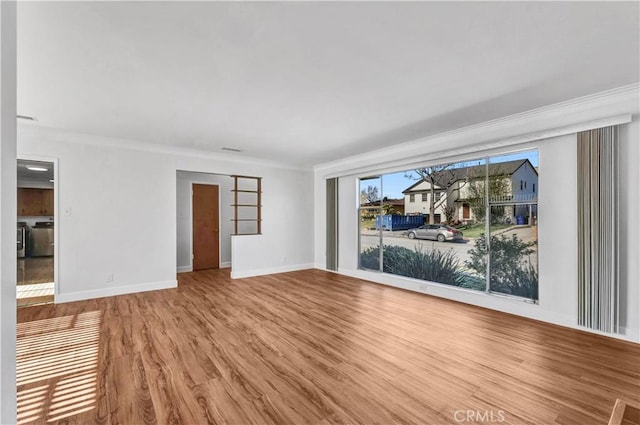 unfurnished room featuring ornamental molding, washer / dryer, and wood-type flooring