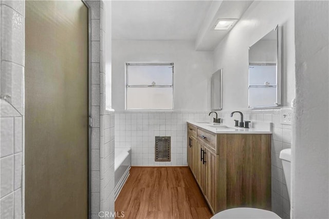 bathroom with toilet, wood-type flooring, vanity, and tile walls