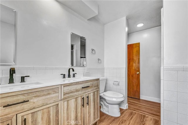 bathroom with tile walls, toilet, hardwood / wood-style floors, and vanity