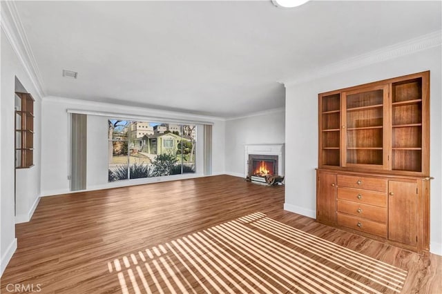 unfurnished living room with hardwood / wood-style floors and ornamental molding