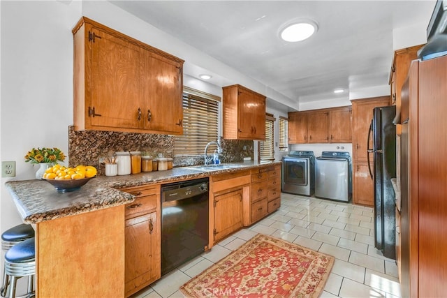 kitchen featuring washer and clothes dryer, light tile patterned floors, tasteful backsplash, black appliances, and sink