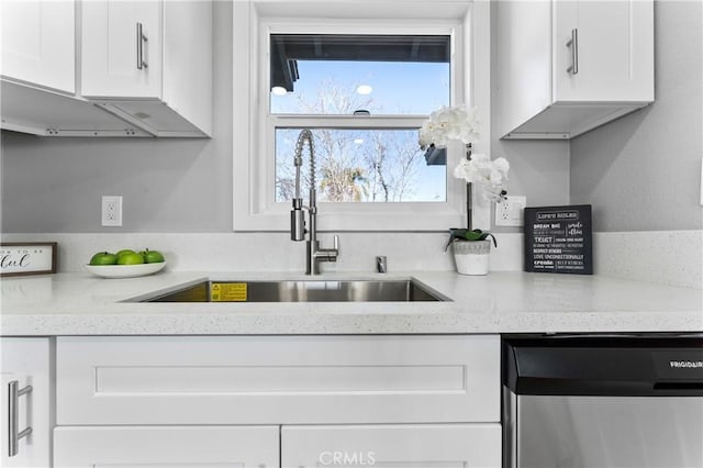 kitchen with light stone counters, white cabinets, dishwasher, and sink