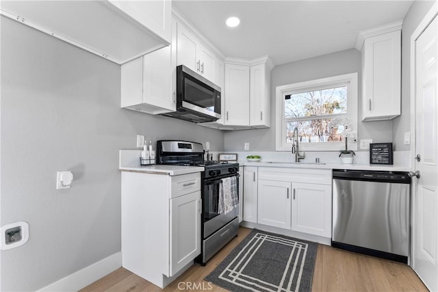 kitchen featuring appliances with stainless steel finishes, light hardwood / wood-style floors, white cabinetry, and sink