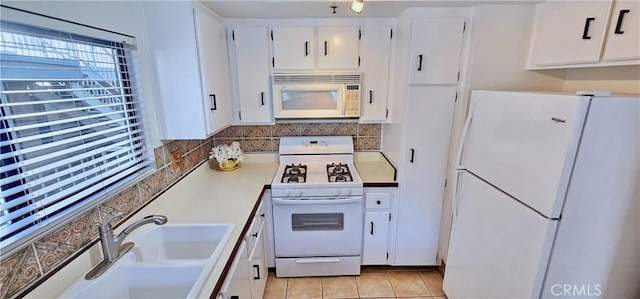 kitchen with white appliances, white cabinets, light tile patterned floors, and sink