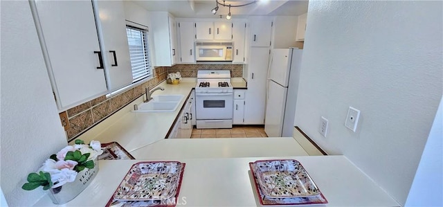 kitchen featuring sink, white cabinets, white appliances, light tile patterned floors, and decorative backsplash