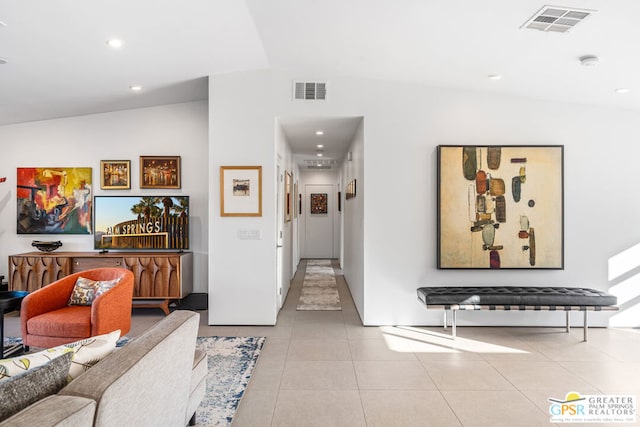 hall featuring light tile patterned flooring and lofted ceiling