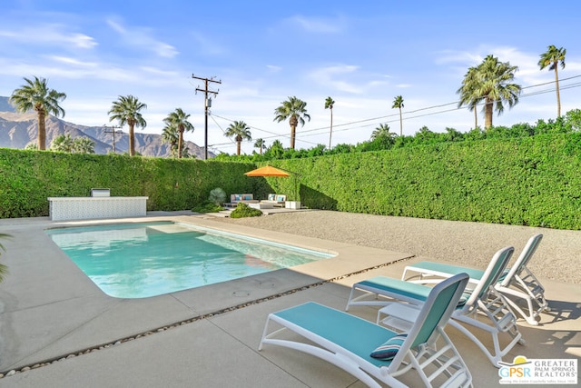 view of swimming pool featuring a patio and a mountain view