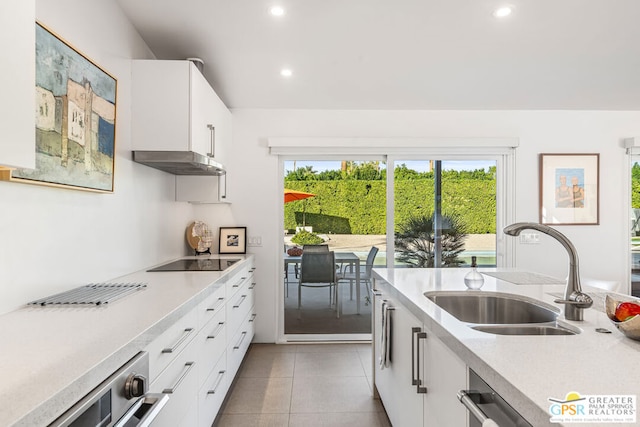 kitchen featuring sink, white cabinetry, black electric stovetop, and light tile patterned floors