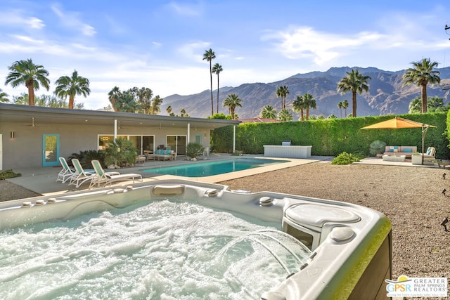 view of swimming pool featuring a hot tub, a patio, and a mountain view