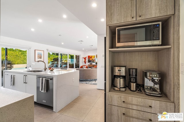 kitchen featuring a center island with sink, light tile patterned flooring, stainless steel dishwasher, and sink