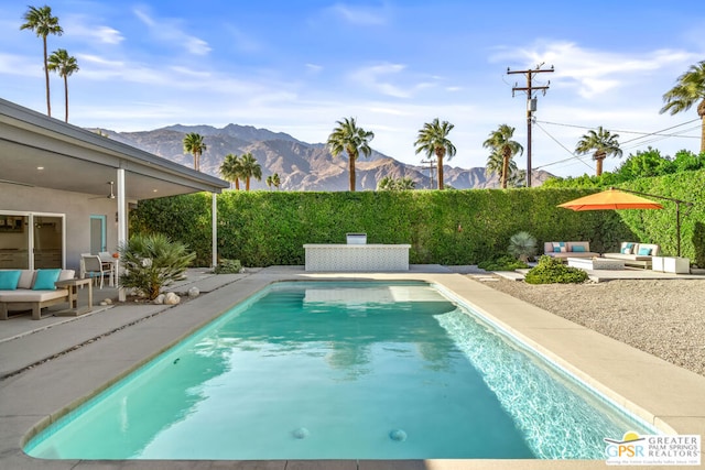 view of swimming pool with ceiling fan, a patio, and a mountain view