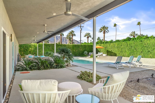 view of patio featuring a mountain view, ceiling fan, a fenced in pool, and an outdoor living space