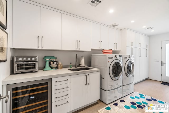 laundry room with beverage cooler, cabinets, separate washer and dryer, and sink