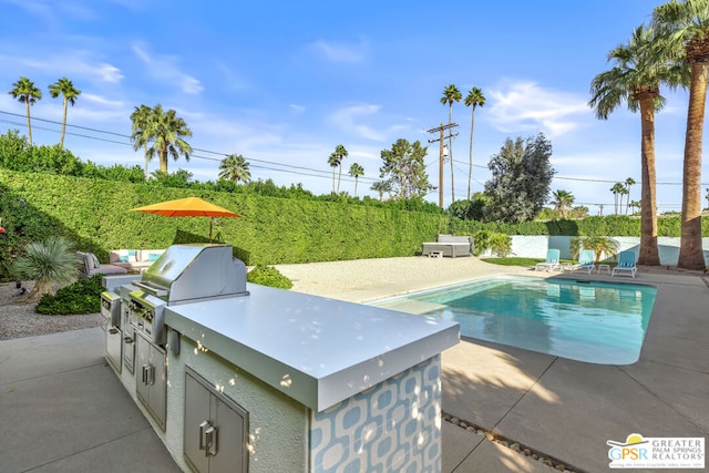 view of pool with area for grilling, an outdoor kitchen, and a patio area