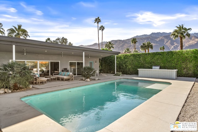 view of swimming pool with a patio area, ceiling fan, outdoor lounge area, and a mountain view