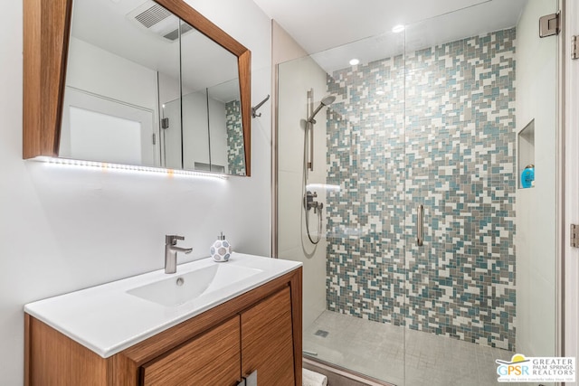 bathroom featuring a shower with door and vanity