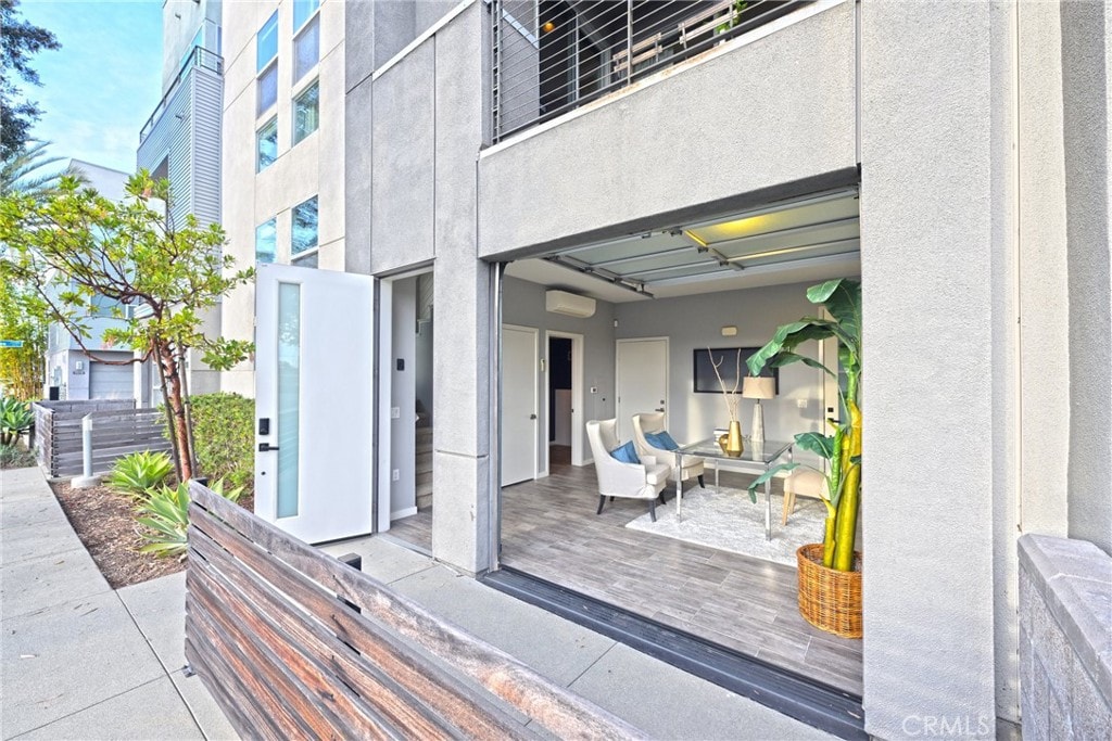 property entrance with an outdoor living space, a wooden deck, and a wall unit AC