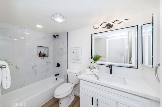 full bathroom featuring tiled shower / bath combo, vanity, hardwood / wood-style flooring, and toilet