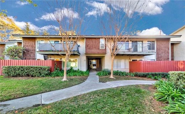 multi unit property featuring a balcony and a front lawn