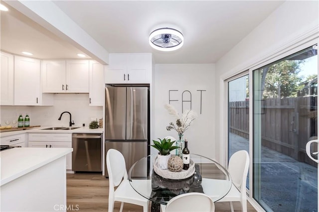 kitchen with sink, light hardwood / wood-style floors, white cabinets, and appliances with stainless steel finishes