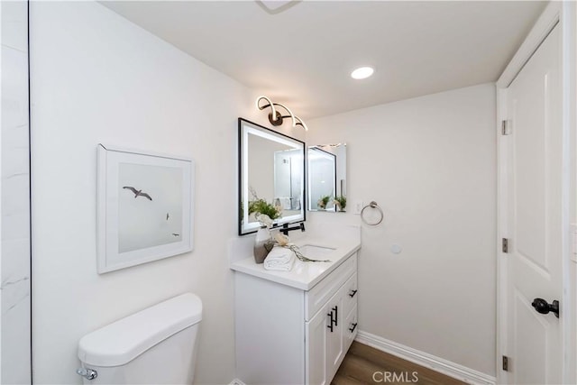 bathroom featuring vanity, wood-type flooring, and toilet