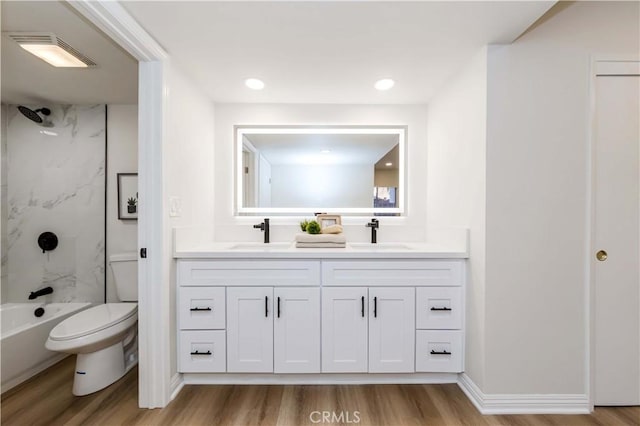 full bathroom with tiled shower / bath, vanity, toilet, and wood-type flooring