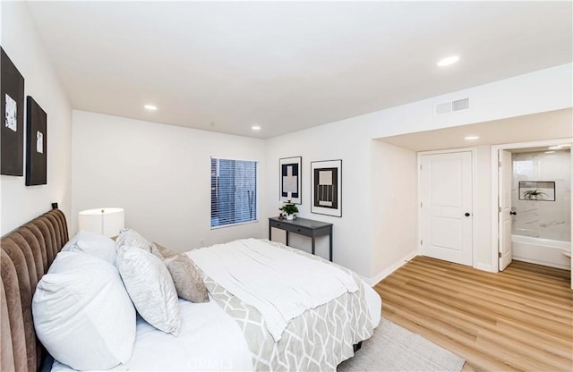 bedroom with ensuite bathroom and hardwood / wood-style floors