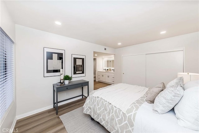 bedroom with hardwood / wood-style flooring, ensuite bathroom, and a closet