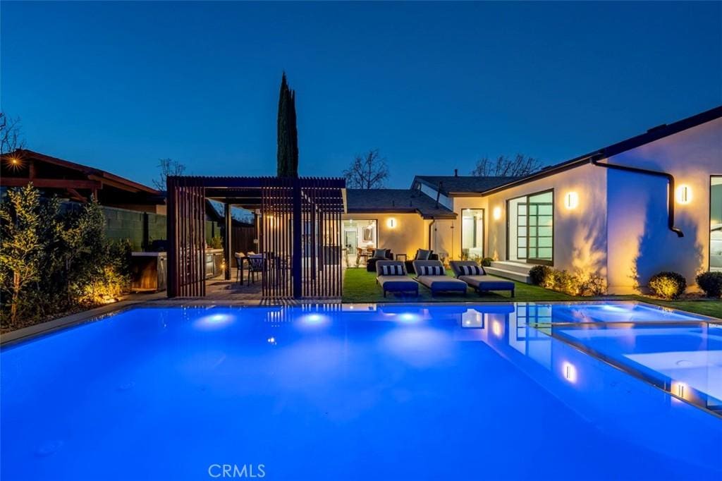 pool at night featuring a pergola and a patio area