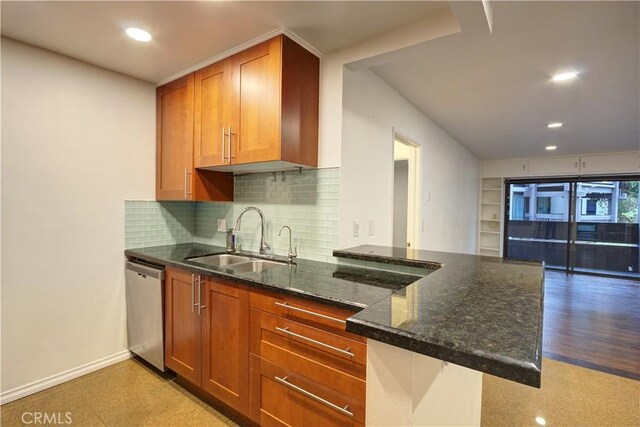 kitchen featuring kitchen peninsula, stainless steel dishwasher, decorative backsplash, dark stone counters, and sink