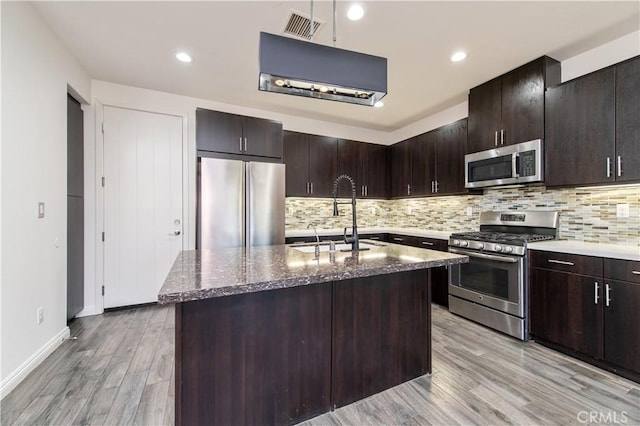 kitchen featuring a kitchen island with sink, dark brown cabinets, sink, and stainless steel appliances