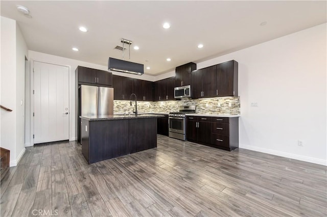 kitchen featuring dark brown cabinetry, appliances with stainless steel finishes, an island with sink, sink, and hardwood / wood-style flooring