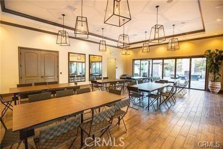 dining space featuring hardwood / wood-style floors, ornamental molding, and a raised ceiling