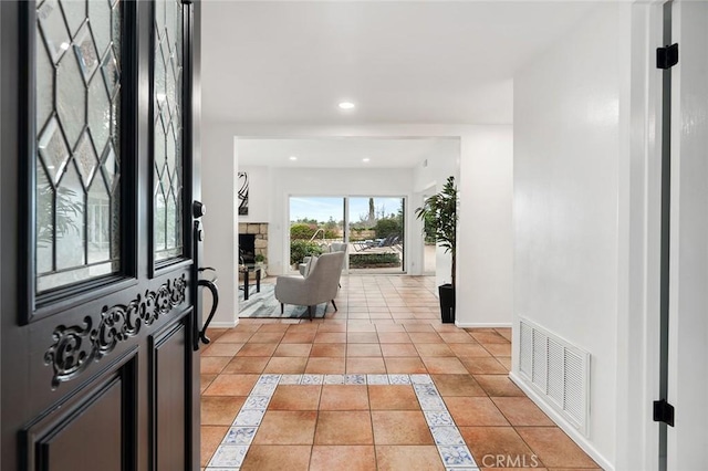 tiled foyer entrance with a stone fireplace