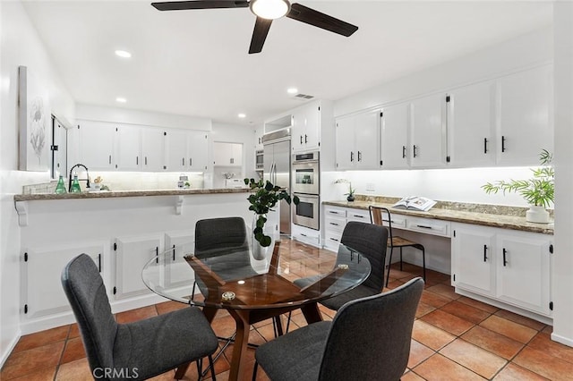 tiled dining space featuring ceiling fan and sink