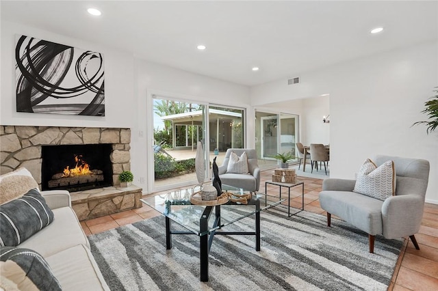 tiled living room with a stone fireplace